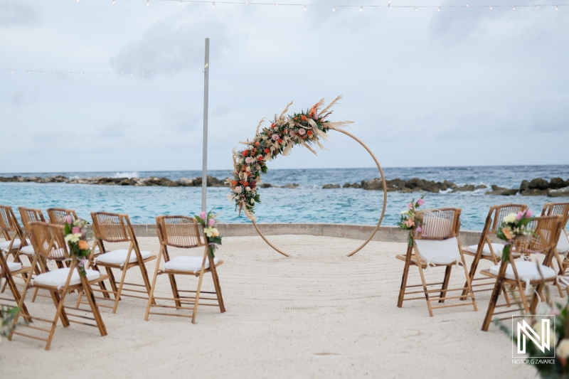 Stunning beach wedding setup at Sunscape Curacao with floral arch and chairs facing the ocean