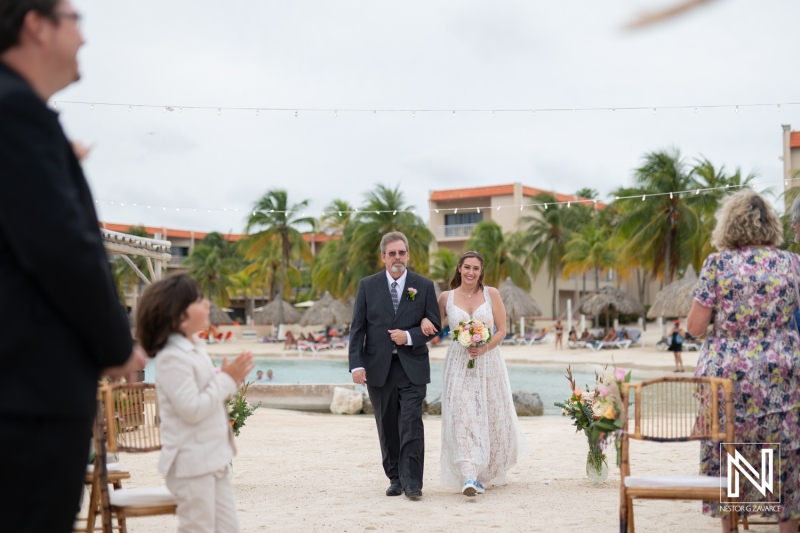 Bride and father walk down the aisle at a romantic wedding in Sunscape Curacao with guests celebrating
