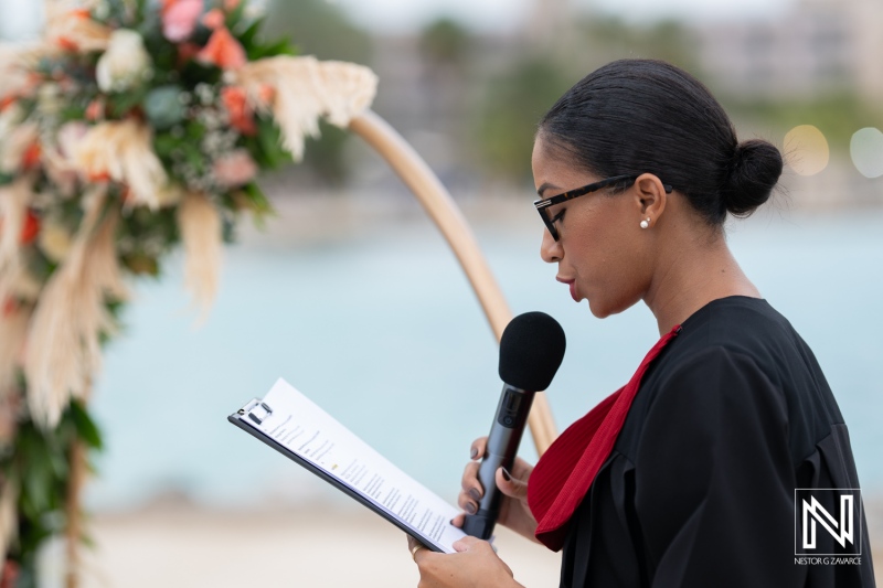 Ceremony officiant speaks during a wedding at Sunscape Curacao with ocean backdrop and floral decorations