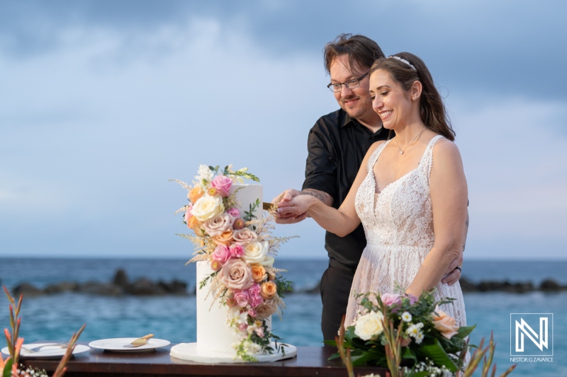 Celebrating love at a beautiful destination wedding in Curacao with a stunning cake by the ocean