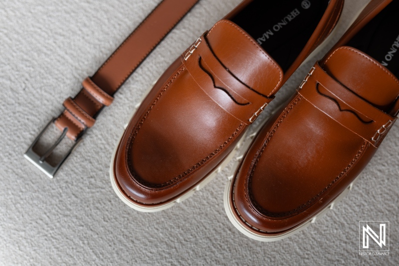 Elegant brown loafers and matching belt on a soft surface create a stylish bridal preparation moment at a wedding in Curacao