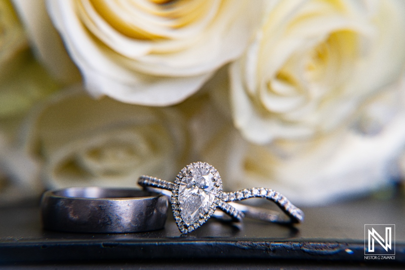 Stunning wedding rings showcase elegance against a backdrop of soft white roses in Curacao