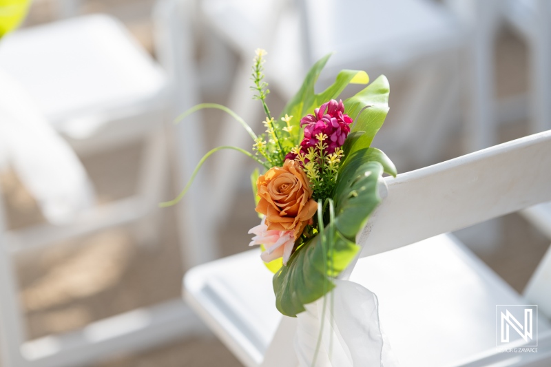 Beautiful floral arrangement decorates white chair at wedding ceremony in Curacao at The Rif at Mangrove Beach Corendon