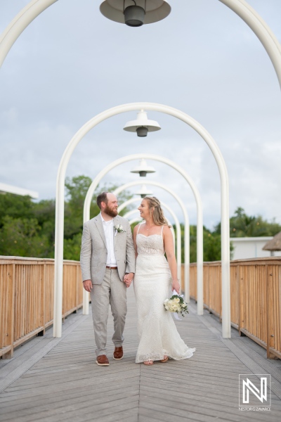 Couple walks hand in hand on a beautiful wooden bridge at Mangrove Beach, celebrating their wedding in Curacao with stunning scenery