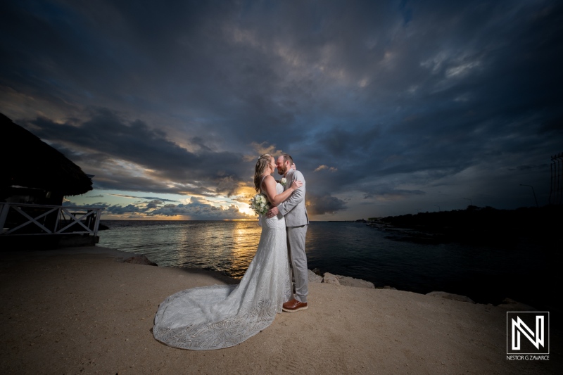 Couple celebrates romantic wedding kiss at sunset on Mangrove Beach in Curacao with stunning ocean backdrop