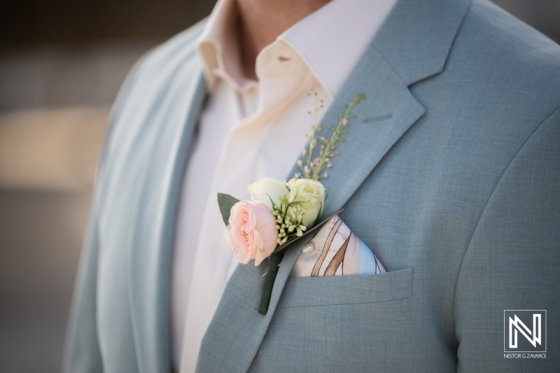 Wedding celebration at Playa Hunku in Curacao with floral details on the groom's suit