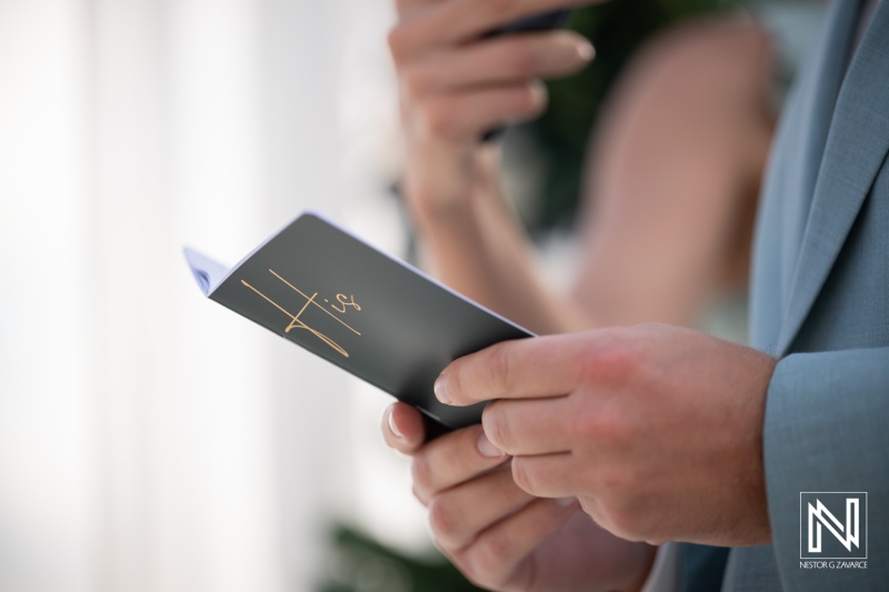 Guests hold wedding programs at Playa Hunku in Curacao during a wedding ceremony