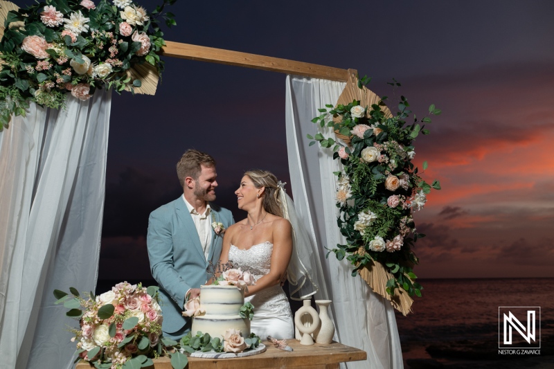 Couple celebrates wedding at Playa Hunku in Curacao with cake and flowers during sunset