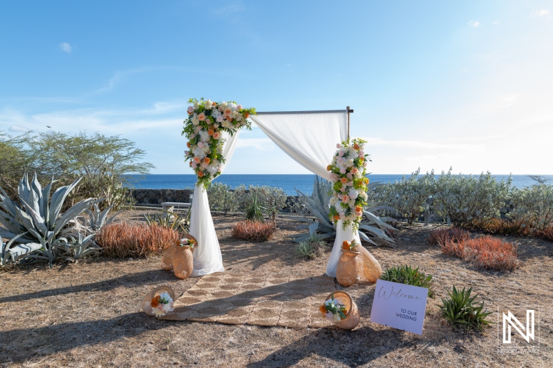 Wedding setup at Westpunt Curacao with floral arch and ocean in background