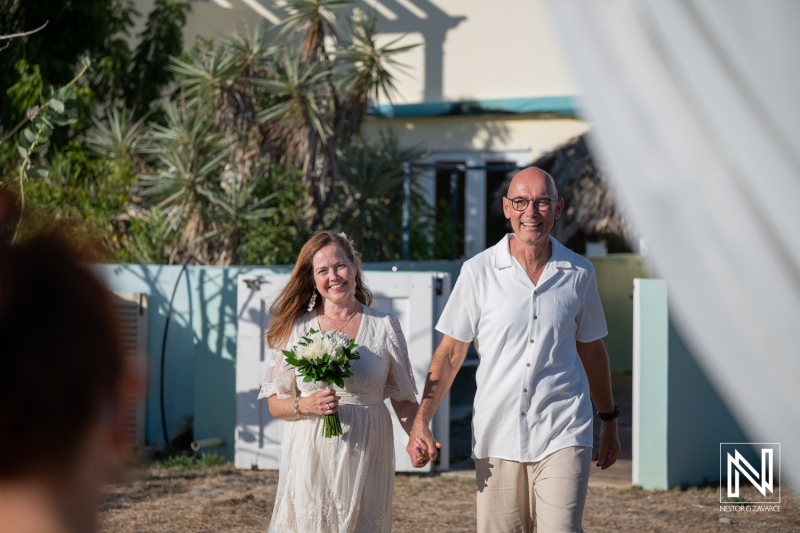 Wedding ceremony with a couple walking together in Westpunt Curacao under bright sunlight