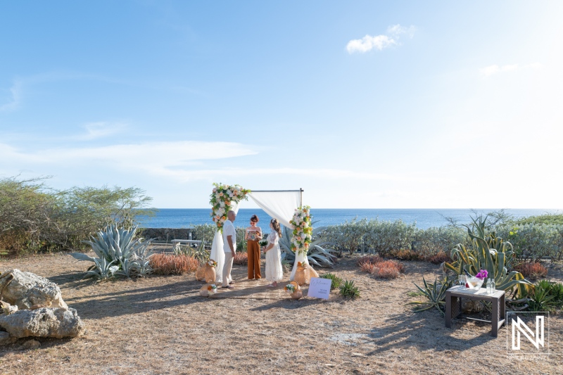 Couple exchanges vows at wedding ceremony in Westpunt Curacao near the ocean with floral decorations