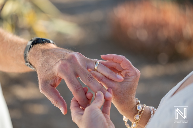 Couple exchanges wedding rings during ceremony in Westpunt Curacao near the beach in the afternoon sun