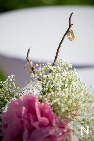 Wedding rings displayed on a branch with flowers at Karakter in Curacao