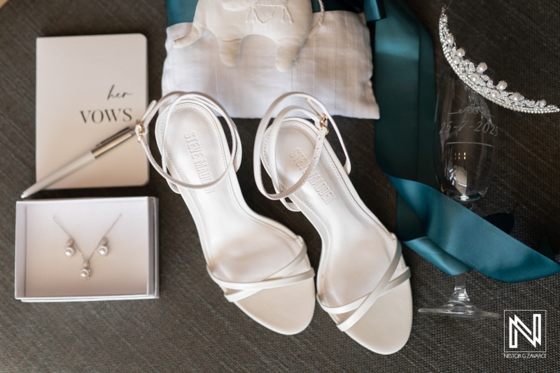 Wedding preparation details featuring elegant white sandals, vow book, and accessories at Karakter in Curacao