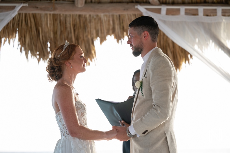 Couple exchanging vows during a beach wedding ceremony at Karakter in Curacao under a beautiful palm-thatched gazebo
