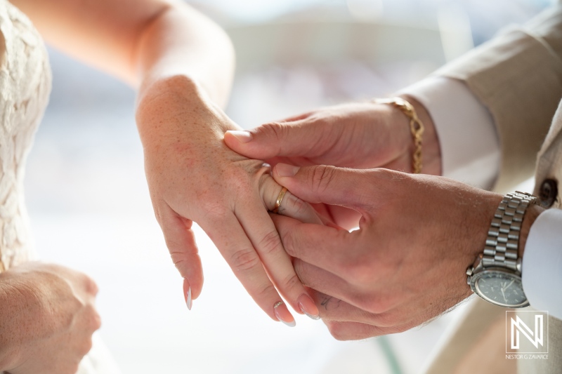 Couple exchanging wedding rings at a beautiful ceremony in Karakter, Curacao surrounded by a scenic beach view