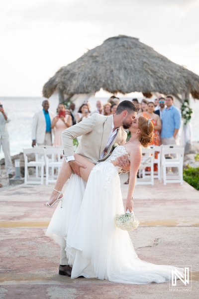 Couple shares a romantic kiss during their wedding ceremony at Karakter in Curacao as guests celebrate the special moment