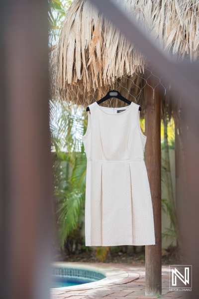 Wedding dress hanging on palapa by the pool
