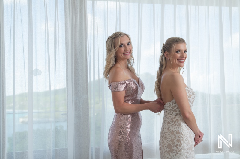 Bridesmaids help bride prepare for wedding at Dreams Curacao Resort with views of the sea