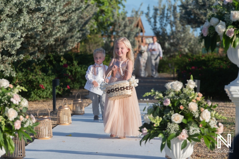 Children walk down the aisle at a wedding ceremony in Dreams Curacao Resort at sunset with flowers and lanterns lining the path