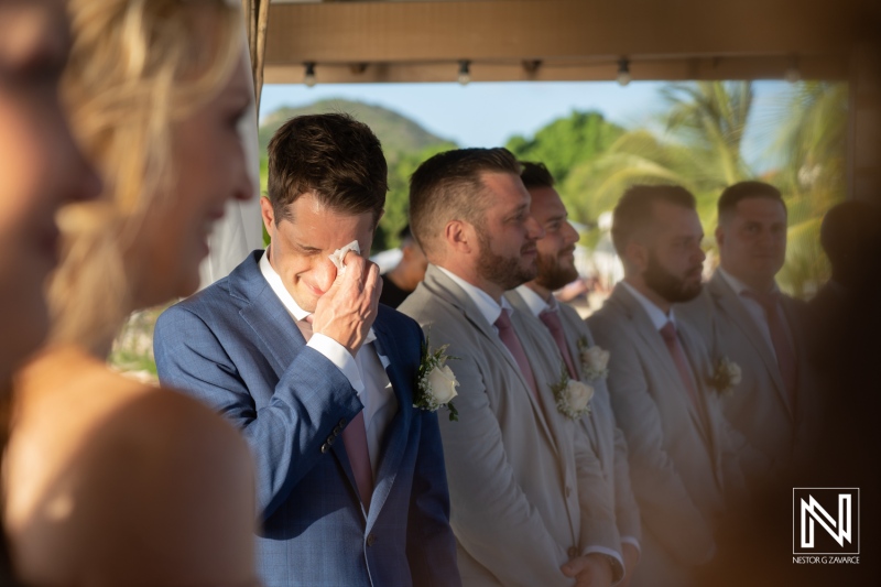 Groom wipes tear while waiting for bride at Dreams Curacao Resort wedding ceremony
