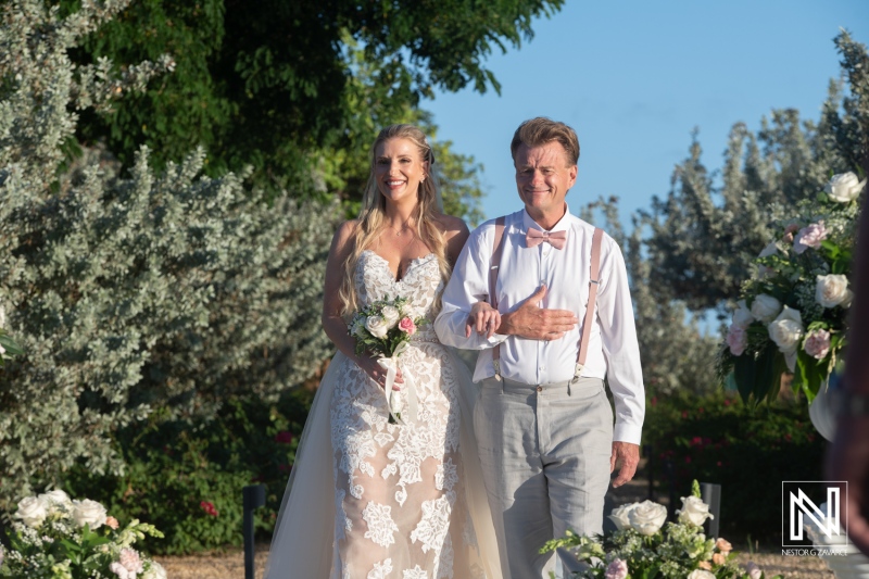 Couple walks down the aisle at wedding ceremony in Dreams Curacao Resort surrounded by flowers and greenery