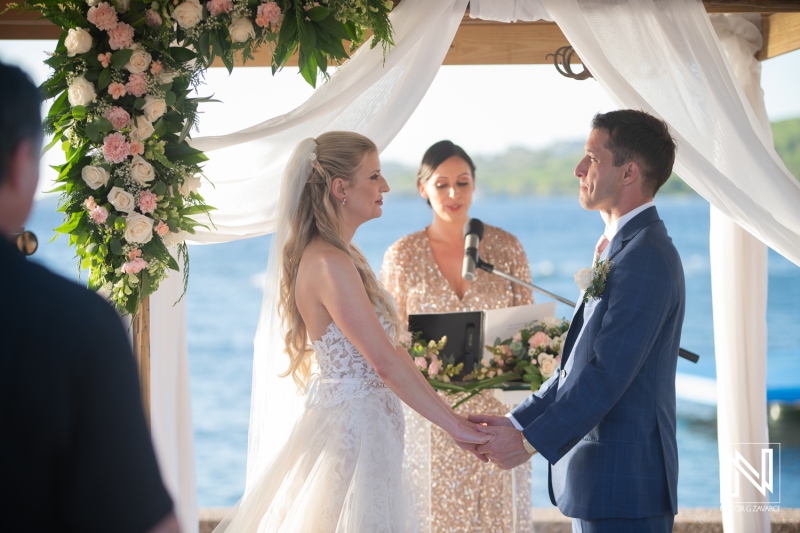 Couple exchanges vows during wedding ceremony at Dreams Curaçao Resort by the water