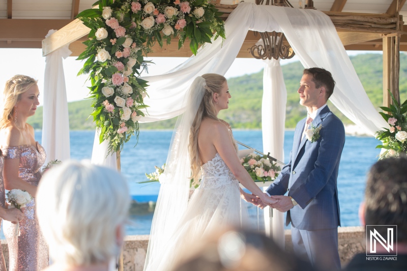 Couple exchanges vows during wedding ceremony at Dreams Curaçao Resort by the ocean in the afternoon sun