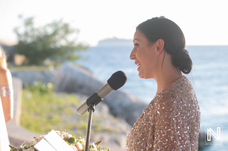 Wedding ceremony at Dreams Curacao Resort by the ocean with a speaker and guests present