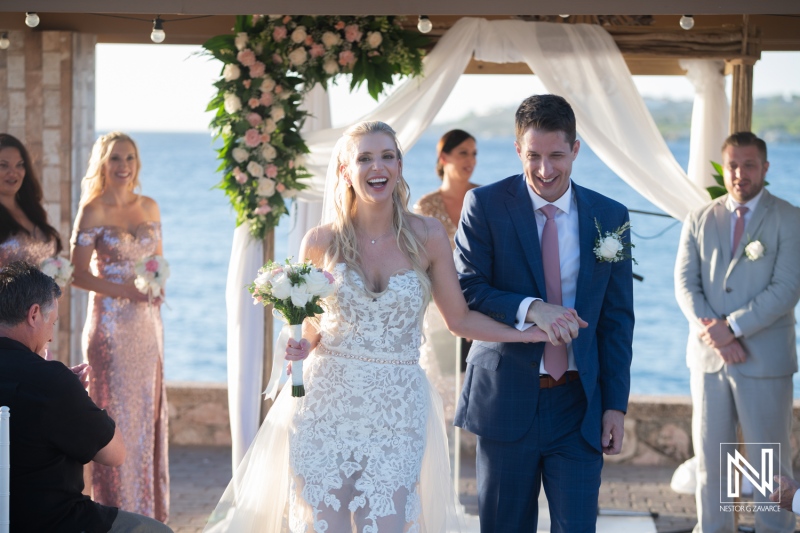 Couple celebrates wedding ceremony at Dreams Curacao Resort by the ocean with guests in attendance