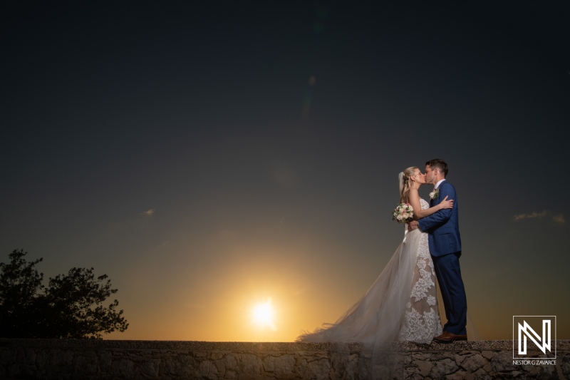 Couple kisses during sunset at wedding ceremony in Dreams Curacao Resort
