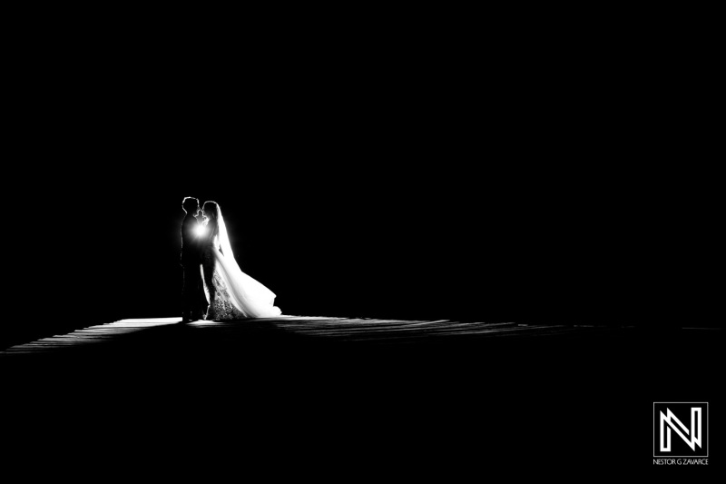 Couple stands close together during wedding ceremony at Dreams Curacao Resort in the evening light