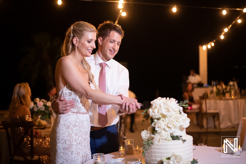 Couple celebrates wedding at Dreams Curacao Resort with cake cutting ceremony and guests nearby