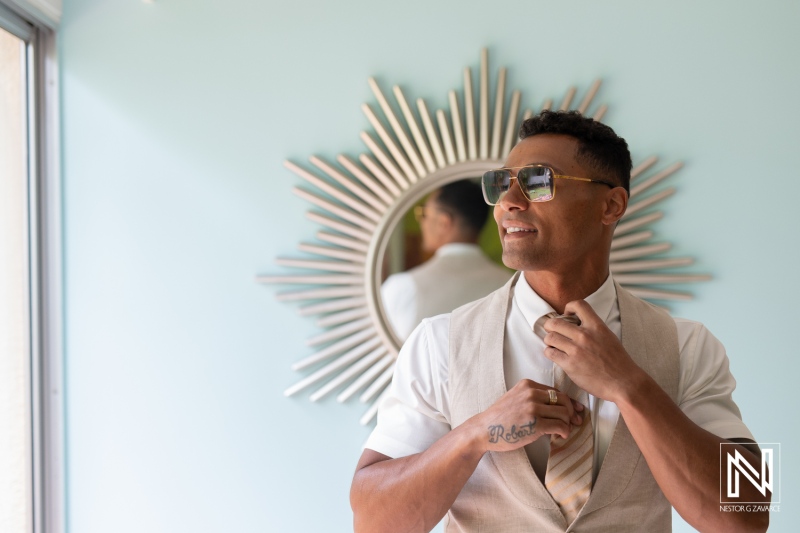 Groom adjusting his tie at Sunscape Curacao Resort before wedding ceremony surrounded by stylish decor and lively atmosphere