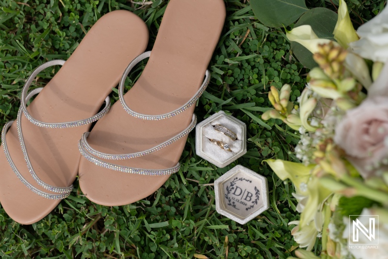 Elegant wedding accessories on the grass at Sunscape Curaçao Resort, featuring sparkling sandals and stunning rings