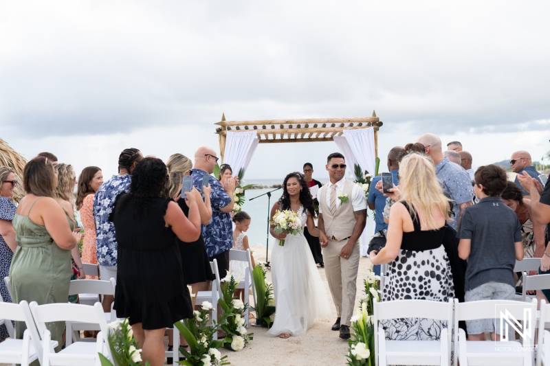 Couple walks down the aisle surrounded by family and friends at a wedding ceremony in Curacao