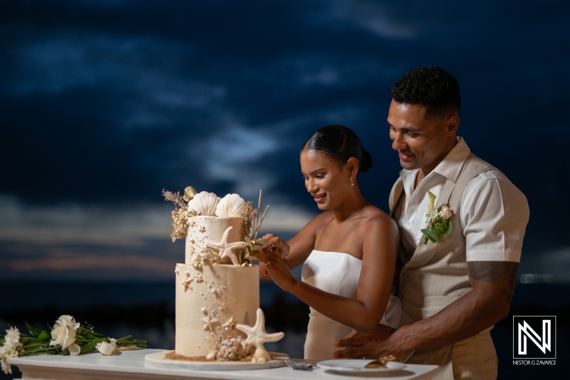 Couple celebrating their wedding cake cutting at Sunscape Curacao Resort under a stunning evening sky