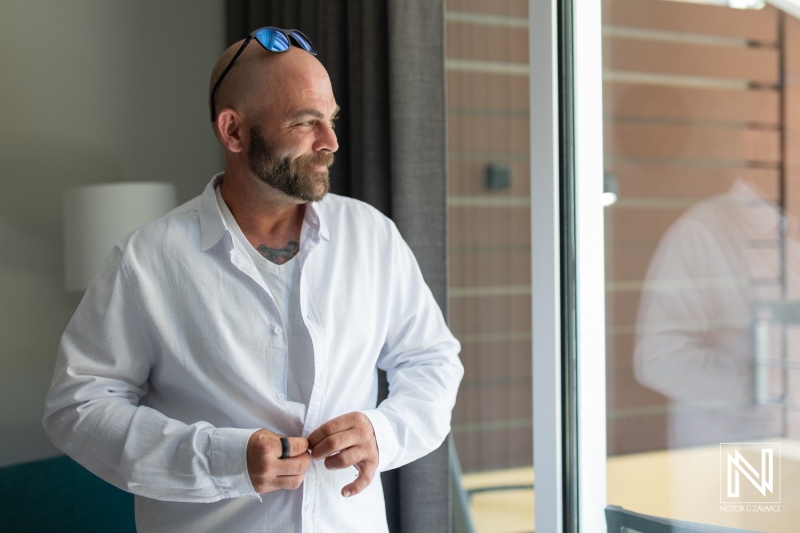 Groom preparing for sunset wedding at Avila Beach Hotel in Curacao with beautiful views