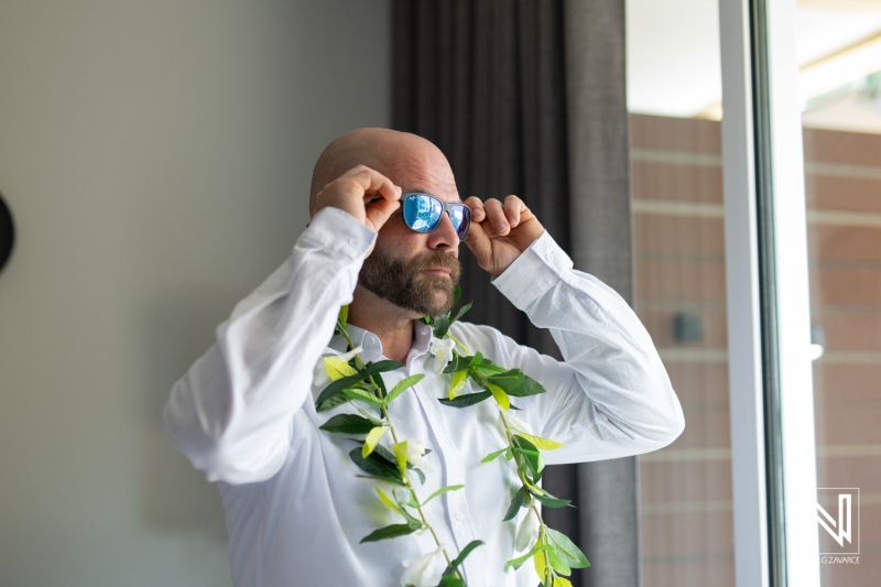 Groom preparing for wedding ceremony at Avila Beach Hotel during stunning sunset in Curacao, surrounded by tropical decor and anticipation