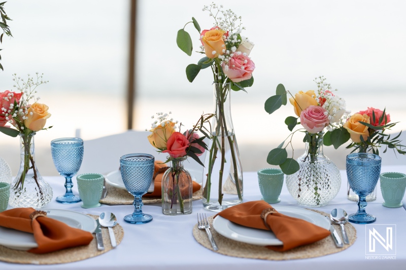 Lovely wedding table setting at Avila Beach Hotel in Curacao during sunset, showcasing vibrant floral arrangements and elegant decor
