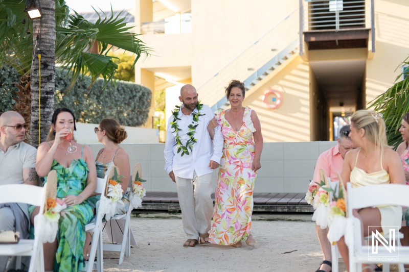 Couple walks down the sandy aisle at sunset wedding ceremony at Avila Beach Hotel in Curacao with guests in attendance