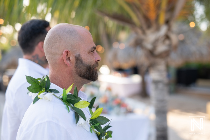 Groom waiting for his bride during a sunset wedding ceremony at Avila Beach Hotel in Curacao with a backdrop of palm trees and soft lighting