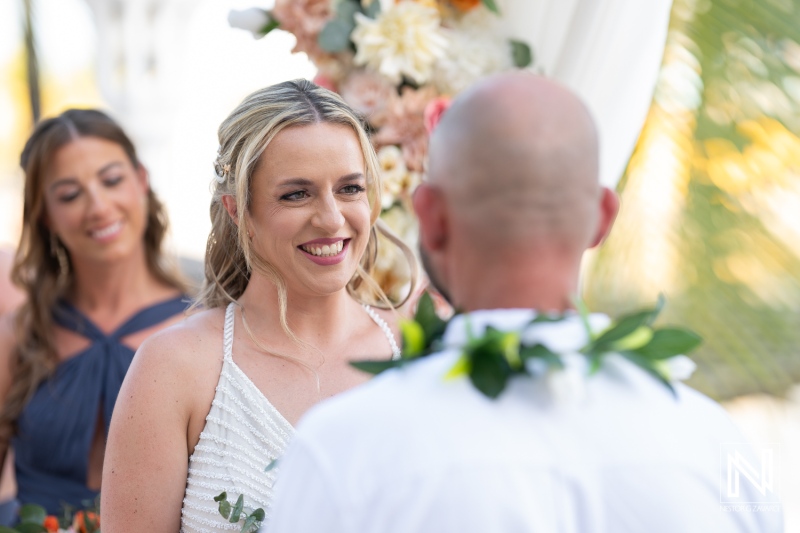 Beautiful wedding ceremony at sunset in Avila Beach Hotel, Curacao with joyful couple and elegant floral decor