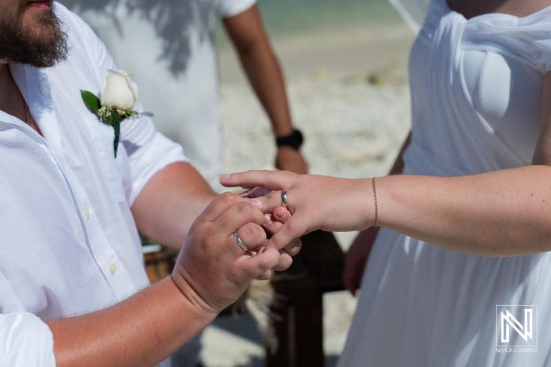 A Beach Wedding Ceremony Takes Place With a Couple Exchanging Rings Under the Sun, Surrounded by Sand and Gentle Ocean Waves