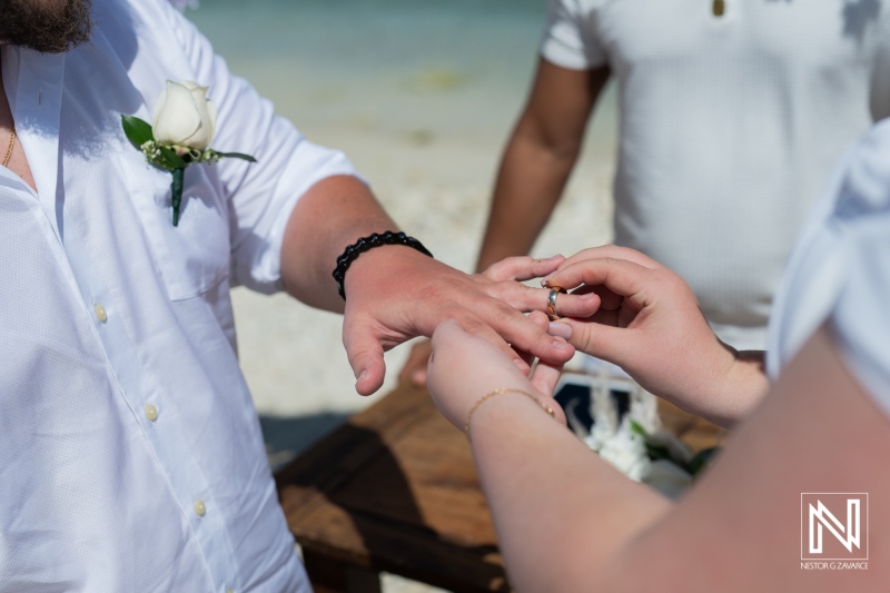 A Couple Exchanging Wedding Rings on the Beach During a Sunny Afternoon Ceremony With a Beautiful Ocean Backdrop