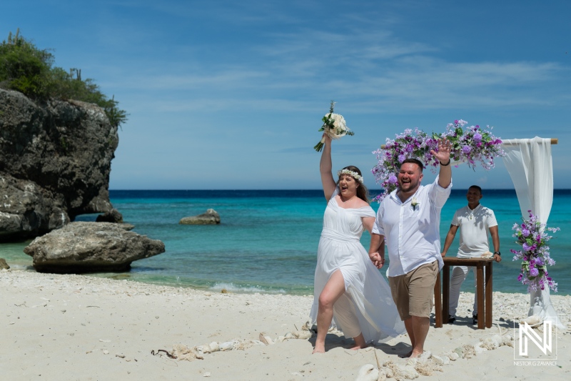 Couple Joyfully Celebrates Their Beach Wedding Ceremony on a Sunny Day by the Ocean, Surrounded by Natural Beauty and Floral Decorations