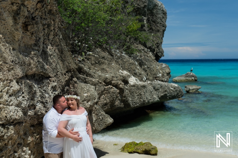 A Couple Celebrates Their Wedding by the Serene Blue Waters and Rocky Coastline of a Tropical Beach on a Sunny Day, Surrounded by Nature and Tranquility