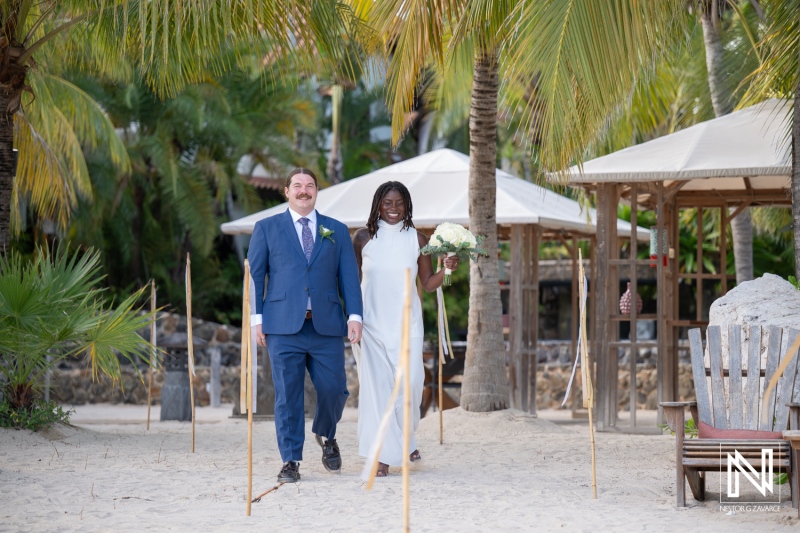 Couple walks hand in hand on the sandy beach at Baoase Luxury Resort during their wedding ceremony in Curacao