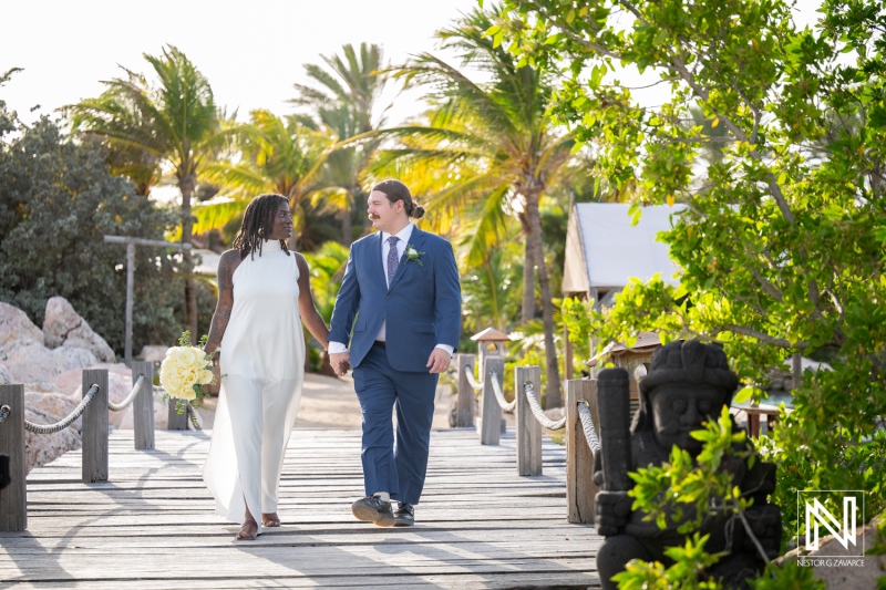 Couple walks hand in hand during their wedding ceremony at Baoase Luxury Resort in Curacao surrounded by tropical scenery