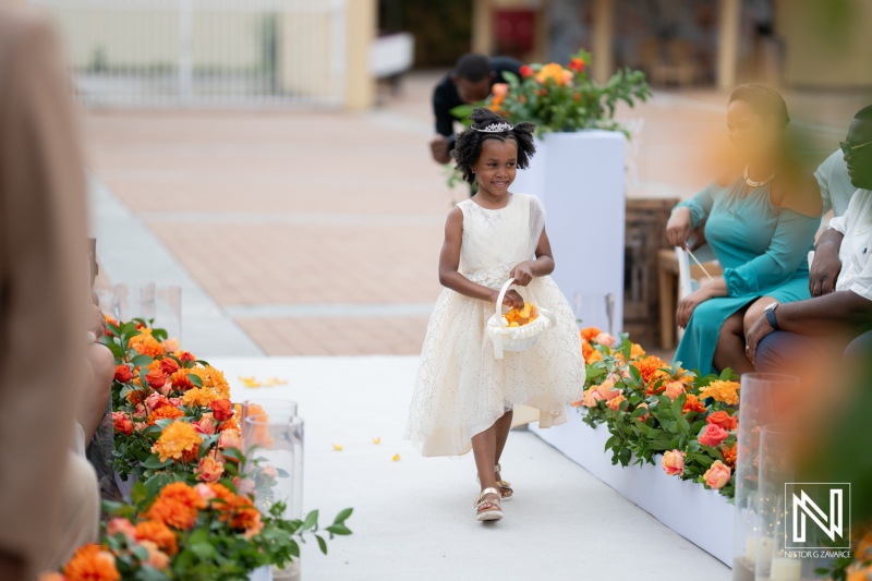 Flower girl joyfully walks down the aisle at a lovely beach wedding in Curacao, creating beautiful memories for all guests